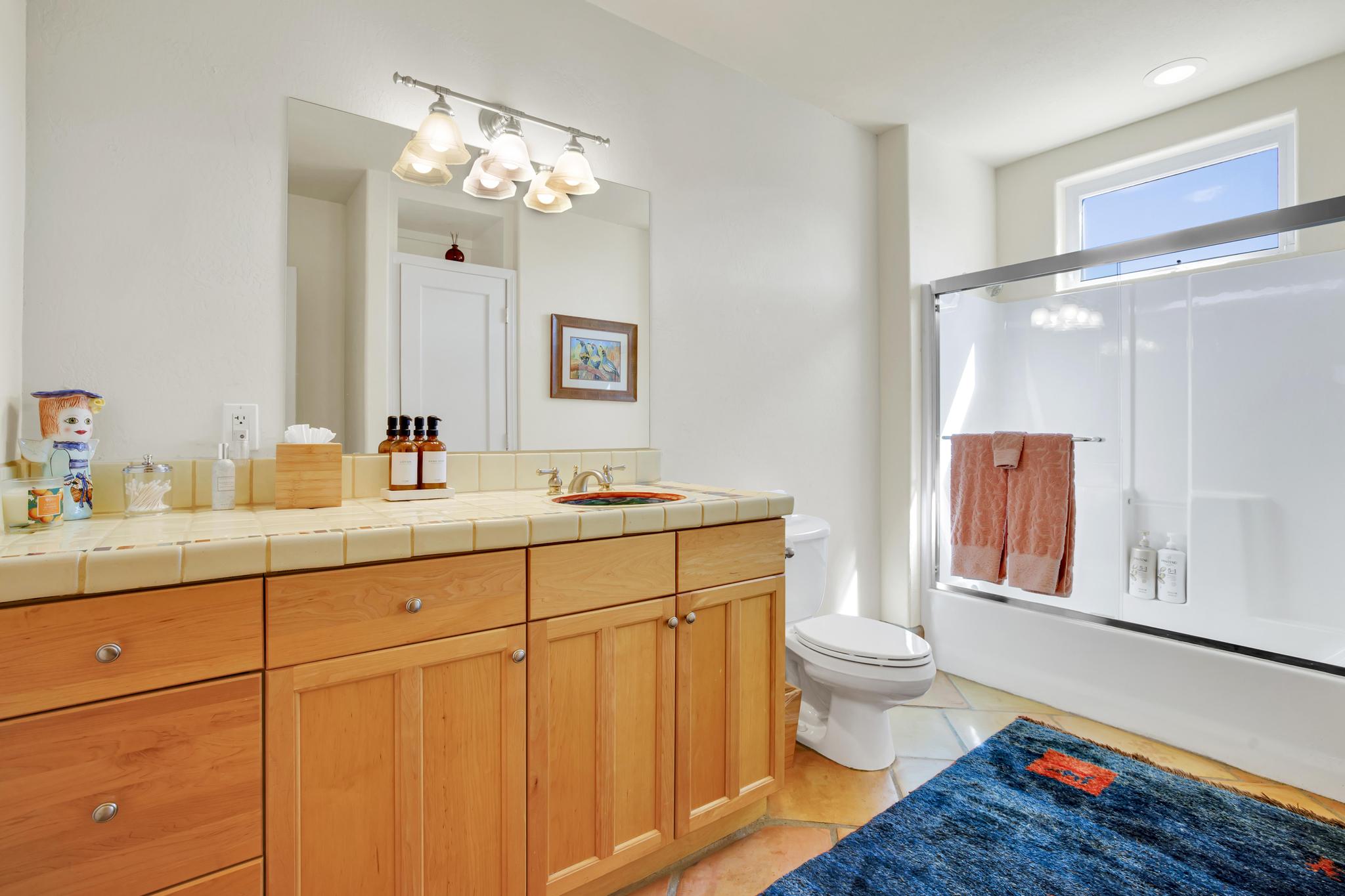 Guest bathroom has a large south facing window with ample vanity space, and a shower/bath combo